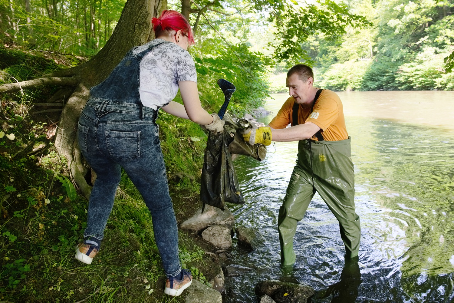 Zwei Personen (Mitarbeitende des IBZ St. Marienthal) entfernen Müll aus dem Fluss Neiße